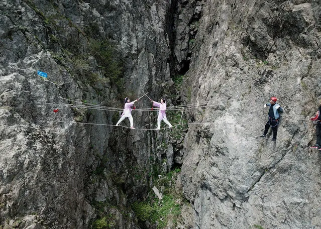 Tour guides step on steel wires between cliffs of Laojun Mountain on the first day of the International Workers' Day holiday on April 29, 2018 in Luoyang, Henan Province of China. Steel wires and stairs have been built on a cliff edge of Laojun Mountain as a new tourism project in Luoyang. Tourists enjoy climbing on the cliff edge during the 3-day International Workers' Day holiday. (Photo by Wang Zhongjun/China News Service/VCG via Getty Images)