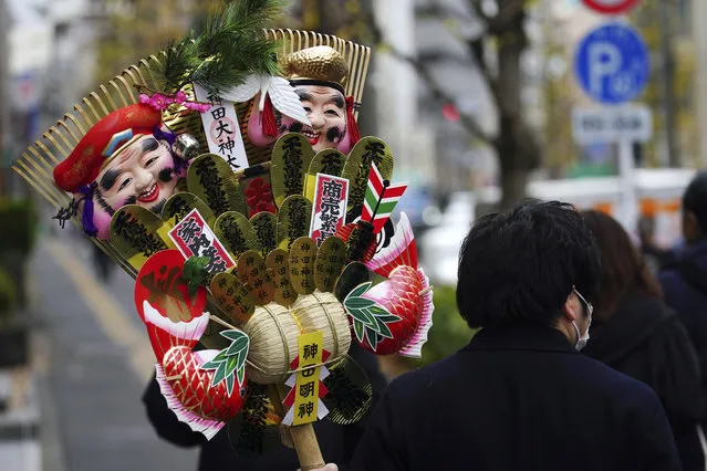 A man wearing a mask against the spread of the coronavirus carries a “kumade” or rake-shaped lucky charm for business during a New Year payer at a shrine Tuesday, January 5, 2021, in Tokyo. (Photo by Eugene Hoshiko/AP Photo)