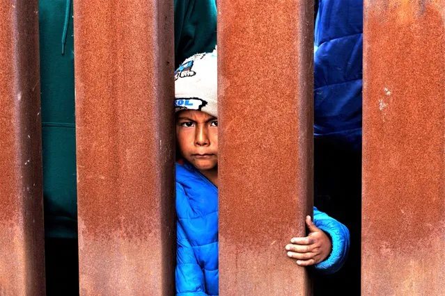 A young migrant boy waits for some food at the border fence while migrants gather between primary and secondary border fences, as the United States prepares to lift COVID-19 era Title 42 restrictions that have blocked migrants at the U.S.-Mexico border from seeking asylum since 2020, near San Diego, California, U.S., May 10, 2023. (Photo by Mike Blake/Reuters)