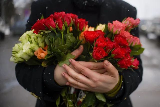 A refugee fleeing the conflict from neighbouring Ukraine holds a bunch of roses, on International Women's Day, at the Romanian-Ukrainian border, in Siret, Romania, Tuesday, March 8, 2022. It is a global day to celebrate women, but many fleeing Ukraine feel only the stress of finding a new life for their children as husbands, brothers and fathers stay behind to defend their country from Russia's invasion. (Photo by Andreea Alexandru/AP Photo)