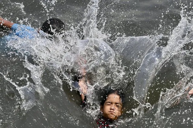 Children swim in the Buriganga River in Dhaka on June 6,  2023. (Photo by Munir Uz Zaman/AFP Photo)