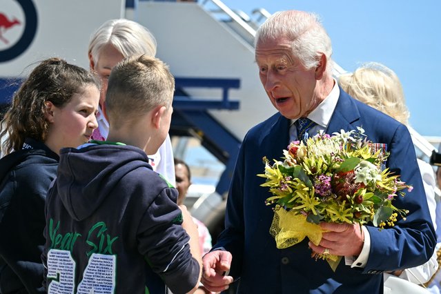 King Charles III talks to children after receiving flowers upon his arrival at Defence Establishment Fairbairn, Canberra Airport on October 21, 2024, in Canberra, Australia. The King's visit to Australia is his first as monarch, and the Commonwealth Heads of Government Meeting (CHOGM) in Samoa will be his first as head of the Commonwealth. (Photo by Saeed Khan/Pool via AFP Photo)