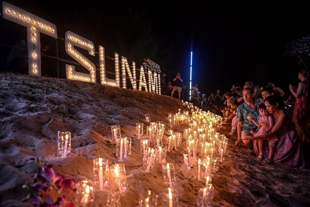 Mourners place candles on the beach at the Ban Nam Khem Tsunami Memorial Park in the southern Thai province of Phang Nga on December 26, 2024. Emotional ceremonies began across Asia on December 26 to remember the 220,000 people who died two decades ago when a tsunami devastated coastal areas around the Indian Ocean, in one of the worst natural disasters in human history. (Photo by Lillian Suwanrumpha/AFP Photo)