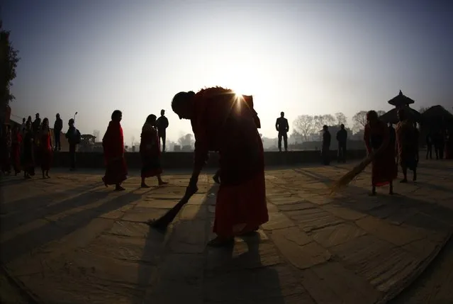 A devotee is silhouetted as she sweeps the floor as devotees (unseen) offer prayer by rolling on the street during the final day of the month-long Swasthani festival at Bhaktapur, near Kathmandu, February 3, 2015. (Photo by Navesh Chitrakar/Reuters)