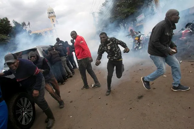 Protestors retreat from a cloud of teargas after police fired canisters at the convoy of opposition leaders led by Raila Odinga during demonstrations against the high cost of living in Nairobi on July 7, 2023. (Photo by Tony Karumba/AFP Photo)