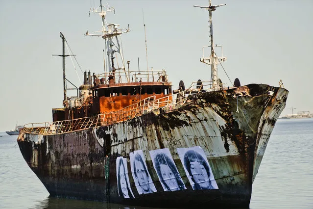 Images of Uruguayans disappeared during the 1973-1985 military dictatorship are displayed on the hull of an abandoned ship aground in the bay of Montevideo, Uruguay, Wednesday, December 21, 2016. The project was initiated by photographer Agustin Fernandez with the support and collaboration of the Mothers and Relatives of Disappeared Detained Uruguayans, to call attention to the lack of investigations regarding these cases. (Photo by Matilde Campodonico/AP Photo)
