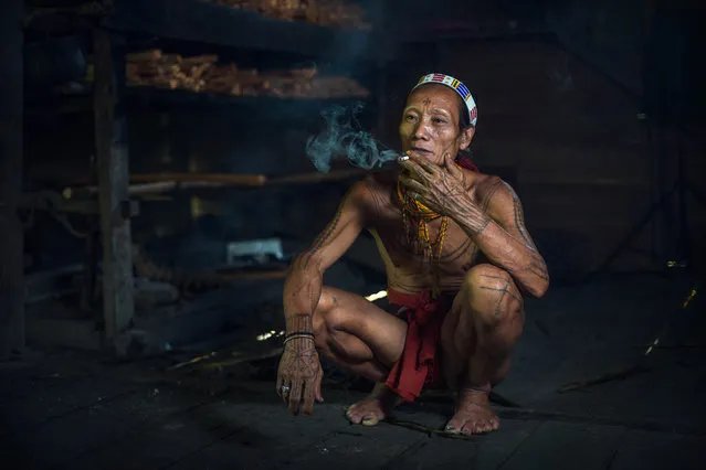 A Mentawai warrior smokes in his home on July 19, 2014 on the Mentawai Islands, Indonesia. (Photo by Muhamad Saleh Dollah/Barcroft Media)