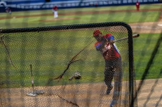 A Cuban baseball player hits the ball during a training session at the Estadio Latinoamericano in Havana, Cuba, Tuesday, May 18, 2021. A little over a week after the start of the Las Americas Baseball Pre-Olympic in Florida, the Cuban team does not have visas to travel to the United States. (Photo by Ramon Espinosa/AP Photo)