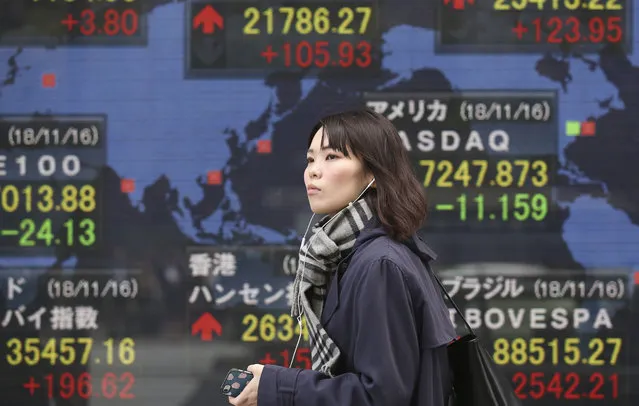A woman walks by an electronic stock board of a securities firm in Tokyo, Monday, November 19, 2018. Asian shares were mostly higher Monday after a buying spree on Wall Street kept up investor optimism into a new week, despite continuing worries about trade tensions. (Photo by Koji Sasahara/AP Photo)
