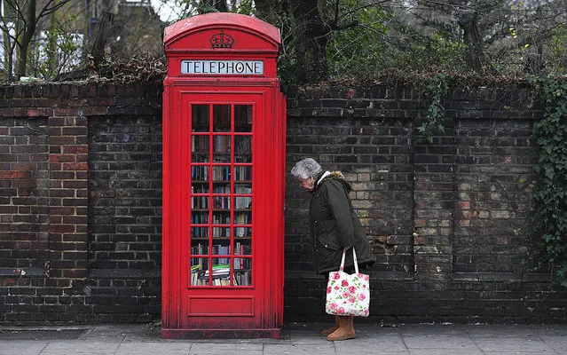 A woman looks at books in a decommissioned red telephone box in London, Britain, 04 January 2017. Sebastian Handley, bought the disused red K2 model for just 1GBP from British Telecom on behalf of the Brockley Society, to becomes London's smallest library. More and more telephone kiosks are being put to inventive uses from members of the public, from miniature art galleries to coffee shops to pint-sized pubs. (Photo by Facundo Arrizabalaga/EPA)