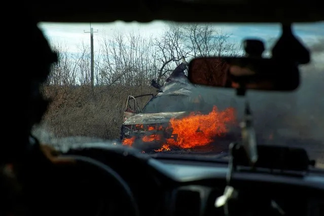 Ukrainian servicemen move past a burning car hit by a kamikaze drone outside the front line town of Avdiivka, amid Russia's attack on Ukraine, in Donetsk region, Ukraine on November 8, 2023. (Photo by Serhiy Nuzhnenko/Radio Free Europe/Radio Liberty)