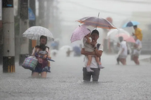 People wade through a road flooded by heavy rain in Kurume, Fukuoka prefecture, western Japan, Saturday, August 14, 2021. Torrential rain pounding southwestern Japan triggered a mudslide early Friday that swallowed some people and was threatening to cause flooding and more landslides in the region. (Photo by Kyodo News via AP Photo)
