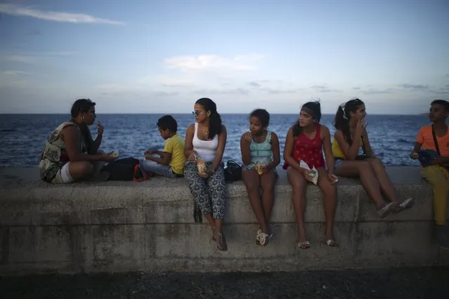Medical student, Lores Valle (3rd L) eats a snack while sitting with relatives at the Malecon in Havana December 29, 2015. (Photo by Alexandre Meneghini/Reuters)