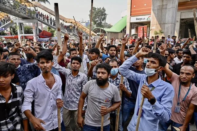 Garment workers block roads as they take part in a protest in Dhaka on November 1, 2023. Thousands of Bangladeshi garment workers barricaded roads in Dhaka Wednesday demanding fair wages for clothing they make for major Western brands, with at least two killed during days of protests. (Photo by Munir Uz Zaman/AFP Photo)