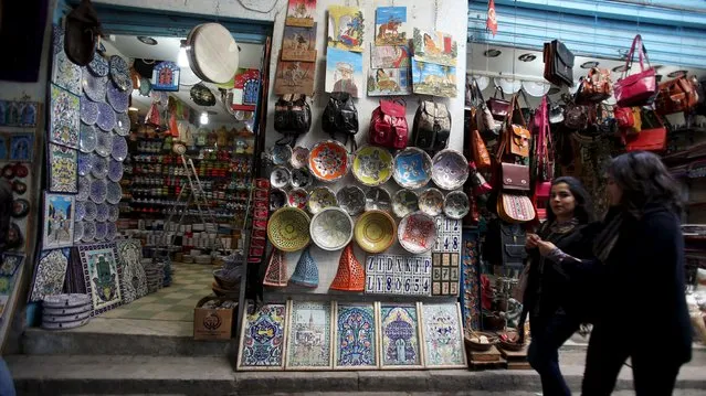 Tunisians walk near at a souvenir shop in the medina, the old city of Tunis, Tunisia, February 16, 2016. (Photo by Zoubeir Souissi/Reuters)