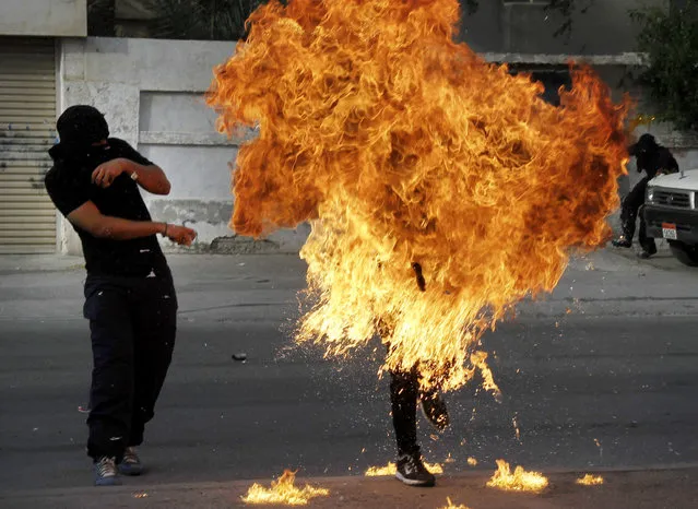 A Bahraini anti-government protester is engulfed in flames when a shot fired by riot police hit the petrol bomb in his hand that he was preparing to throw during clashes in Sanabis, Bahrain, Thursday, March 14, 2013. (Photo by Hasan Jamali/AP Photo)