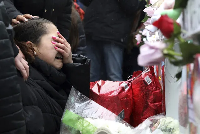 One of victim Vicente Juarez's daughter Diana Juarez cries at a makeshift memorial Sunday, February 17, 2019, in Aurora, Ill., near Henry Pratt Co. manufacturing company where several were killed on Friday. Authorities say an initial background check five years ago failed to flag an out-of-state felony conviction that would have prevented a man from buying the gun he used in the mass shooting in Aurora. (Photo by Nam Y. Huh/AP Photo)