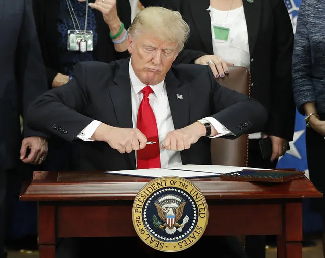 President Donald Trump takes the cap off a pen before signing executive order for immigration actions to build border wall during a visit to the Homeland Security Department in Washington, Wednesday, January 25, 2017. (Photo by Pablo Martinez Monsivais/AP Photo)