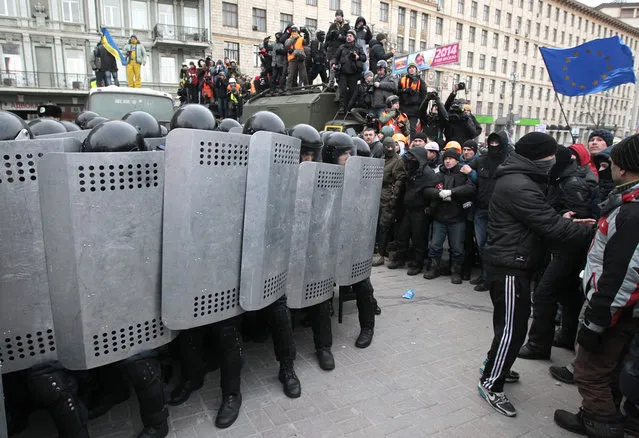 Protesters attack riot police in central Kiev, on January 19, 2014. A group of radical activists began attacking riot police with sticks, trying to push their way toward the Ukrainian parliament building, which has been cordoned off by rows of police vehicles and buses. (Photo by Sergei Chuzavkov/AP Photo)