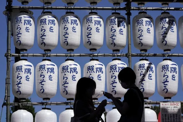 Visitors check their fortune-telling paper strips at a shrine Monday, Sept. 20, 2021 in Tokyo. Japanese words on the lantern reads, “Illuminate a corner”. (Photo by Eugene Hoshiko/AP Photo)