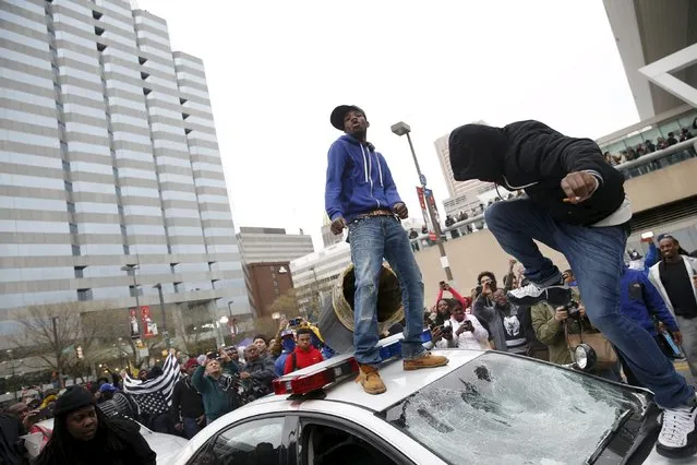 Protesters jump on a police car at a rally to protest the death of Freddie Gray who died following an arrest in Baltimore, Maryland April 25, 2015. (Photo by Shannon Stapleton/Reuters)