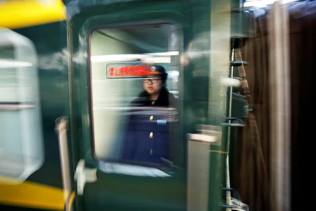 A railway worker looks from inside a train departing the Beijing Railway Station in central Beijing, China January 27, 2017 as China gears up for Lunar New Year, when hundreds of millions of people head home. (Photo by Damir Sagolj/Reuters)