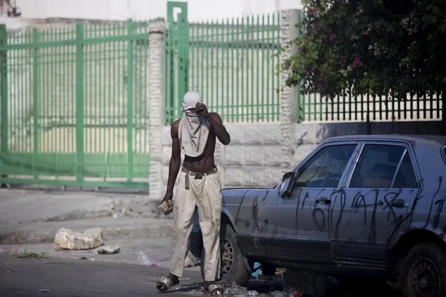 A protester holds a rock during a protest to demand the resignation of President Jovenel Moise and demanding to know how Petro Caribe funds have been used by the current and past administrations, in Port-au-Prince, Haiti, Saturday, February 9, 2019. Much of the financial support to help Haiti rebuild after the 2010 earthquake comes from Venezuela's Petro Caribe fund, a 2005 pact that gives suppliers below-market financing for oil and is under the control of the central government. (Photo by Dieu Nalio Chery/AP Photo)