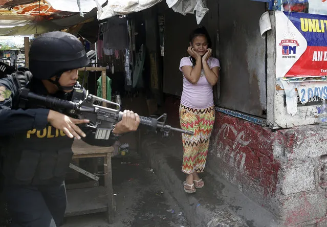 A resident cries as a SWAT member of the Philippine National Police searches for residents who allegedly threw rocks at them as they enforce the demolition of their shanties at the sprawling community of informal settlers Monday, January 27, 2014 at suburban Quezon city, northeast of Manila, Philippines. The demolition was carried out by the city government to pave the way for the commercial development of the area. (Photo by Bullit Marquez/AP Photo)