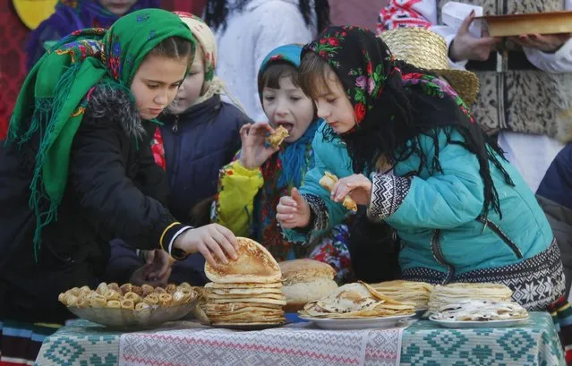 Belarusian children eat pancakes during Maslenitsa celebrations, or Shrovetide, in the village of Otradnoye, 150 km (93 miles) south of Minsk, Belarus, Sunday, March 13, 2016. (Photo by Sergei Grits/AP Photo)