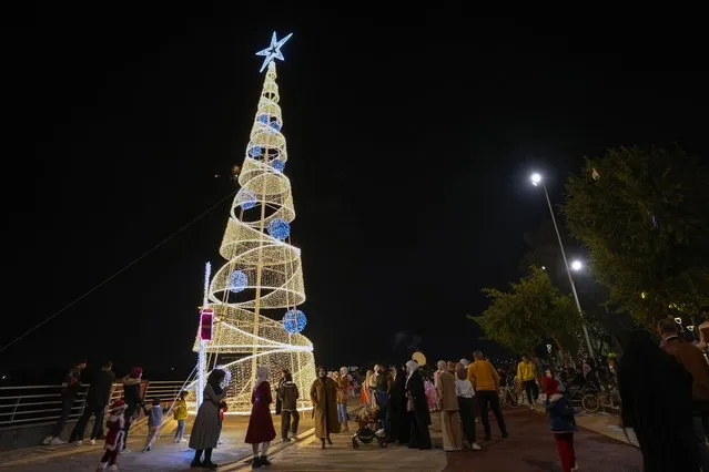 Iraqis gather to celebrate the New Year around a Christmas tree in Baghdad, Iraq, Sunday, December 31, 2023. (Photo by Hadi Mizban/AP Photo)