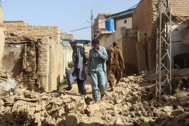 Residents walk amid the rubble of damaged houses along a street following an earthquake in Harnai, Balochistan, Pakistan, October 7, 2021. (Photo by Naseer Ahmed/Reuters)