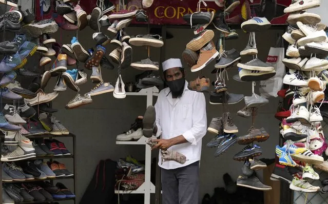 A Sri Lankan man displays used shoes for sale at his shop after easing of restrictions that were imposed to curb the spread of the coronavirus in Colombo, Sri Lanka, Friday, October 1, 2021. (Photo by Eranga Jayawardena/AP Photo)