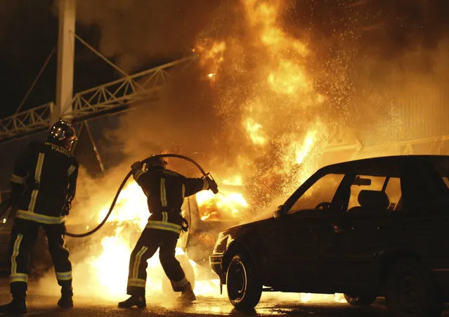 In this November 8, 2005 file photo, firefighters work to extinguish burning cars set on fire by rioters in Gentilly, south of Paris, France. Two young boys were electrocuted in a power substation in Clichy-sous-Bois, while hiding from police on October 27, 2005. The boys' deaths led to three weeks of nationwide riots by those who see police not as protectors but as predators. (Photo by Michel Spingler/AP Photo)