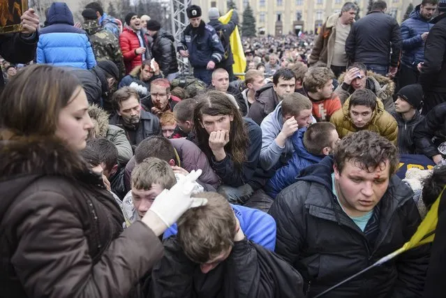 Wounded supporters of Ukraine's new government sit on the ground after clashes with pro-Russian protesters in central Kharkiv March 1, 2014. (Photo by Reuters/Stringer)