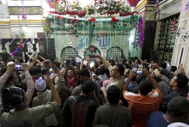 Egyptians reach to touch the shrine of Sayida Zeinab as people celebrate the birthday of Sayida Zeinab, the granddaughter of Prophet Mohammad, in Cairo, May 12, 2015. Picture taken May 12, 2015. (Photo by Mohamed Abd El Ghany/Reuters)