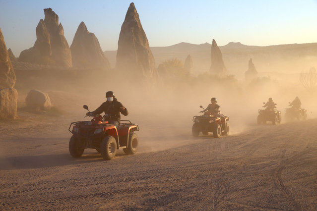 Tourists ride ATVs (all-terrain vehicle) while touring the chimney rocks at Gulludere Valley at the historical Cappadocia region, located in Central Anatolia's Nevsehir province, Turkey on October 24, 2021. Cappadocia is preserved as a UNESCO World Heritage site and is famous for its chimney rocks, hot air balloon trips, underground cities and boutique hotels carved into rocks. In Turkey's one of the most important tourism regions Cappadocia, local and foreign tourists get the chance of enjoying the scenery by participating air balloon tours in the early hours of the morning, riding horse and camel, touring by all-terrain vehicle (ATV) and walking among the fairy chimneys. (Photo by Behcet Alkan/Anadolu Agency via Getty Images)