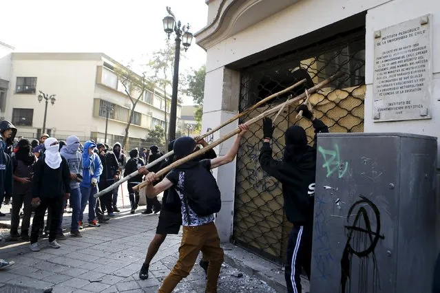 Protesters hit a drugstore during a demonstration to demand changes in the education system at Santiago, May 14, 2015. (Photo by Ivan Alvarado/Reuters)