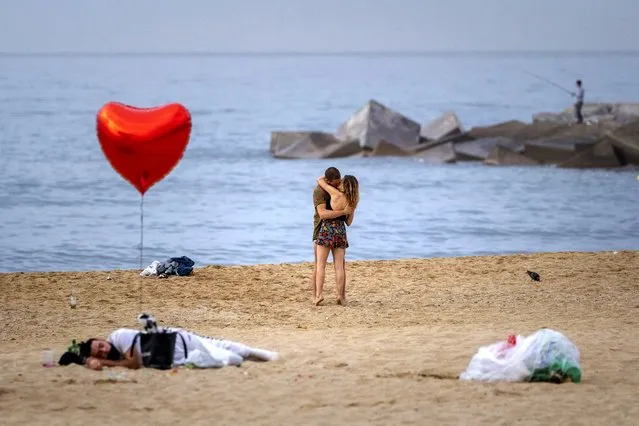 A couple kiss at a beach early in the morning in Barcelona, Spain, Sunday, June 20, 2021. (Photo by Emilio Morenatti/AP Photo)