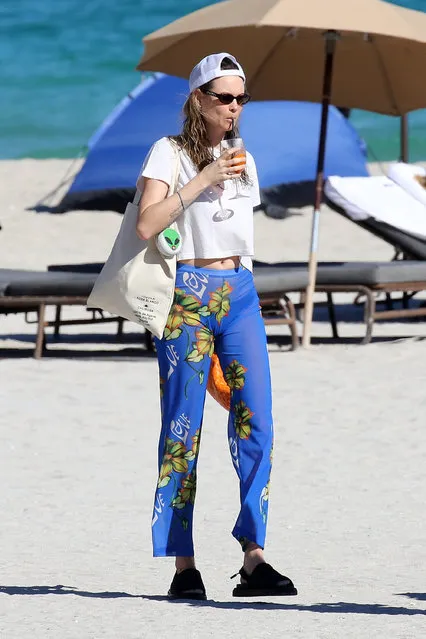 Namibian model Behati Prinsloo wears sheer blue pants and sips a refreshing cocktail as she takes a walk on the beach in Miami on December 1, 2021. (Photo by The Mega Agency)