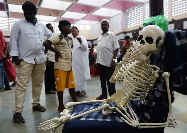 Bystanders look a replica of human skeleton smoking cigarette during an awareness rally on occasion of the “World No-Tobacco Day”, in Chennai on May 31, 2019. World No-Tobacco Day is observed every year on May 31 to raise awareness on the harmful and deadly effects of tobacco and to discourage the use of tobacco in any form. (Photo by Arun Sankar/AFP Photo)