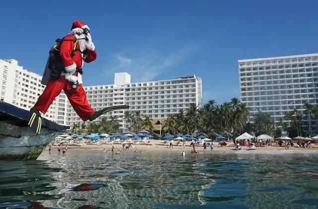 A man disguised as Santa Claus jumps into the water in the beach of Acapulco, state of Guerrero, Mexico, on December 21, 2021. (Photo by Francisco Robles/AFP Photo)