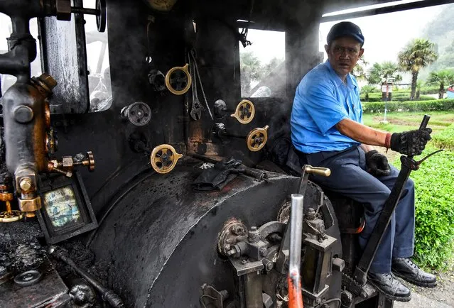 Train driver Hari Chettri sits in the engine of Darjeeling Himalayan Railway steam train, which runs on a 2 foot gauge railway and is a UNESCO World Heritage Site, as it leaves Batasia Loop in Darjeeling, India, June 25, 2019. (Photo by Ranita Roy/Reuters)