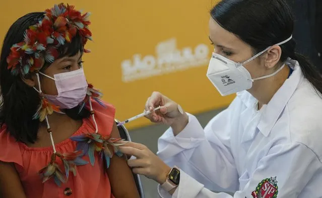 A health worker gives a shot of the Pfizer COVID-19 vaccine to 9-year-old Indigenous youth Stella Para Poty Fernandes Martins at the Hospital da Clinicas in Sao Paulo, Brazil, Friday, January 14, 2022. The state of Sao Paulo started the COVID-19 vaccination of children between ages 5 and 11. (Photo by Andre Penner/AP Photo)
