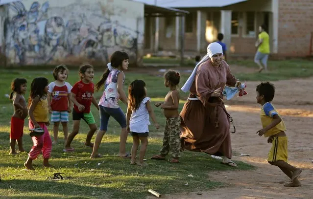 A sister of the Franciscan order plays with children in Lambare city, near Asuncion, April 2, 2014. The poverty rate in Paraguay fell 8.6 percentage points in 2011-2013 to 23.8 percent, the government reported on Wednesday, attributing this to an increase in employment and welfare programs. (Photo by Jorge Adorno/Reuters)