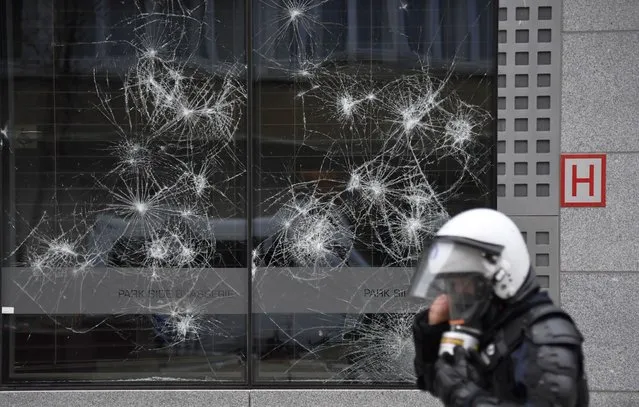 A police officer walks by a damaged building in the European Union quarter during a demonstration against COVID-19 measures in Brussels, Sunday, January 23, 2022. (Photo by Geert Vanden Wijngaert/AP Photo)