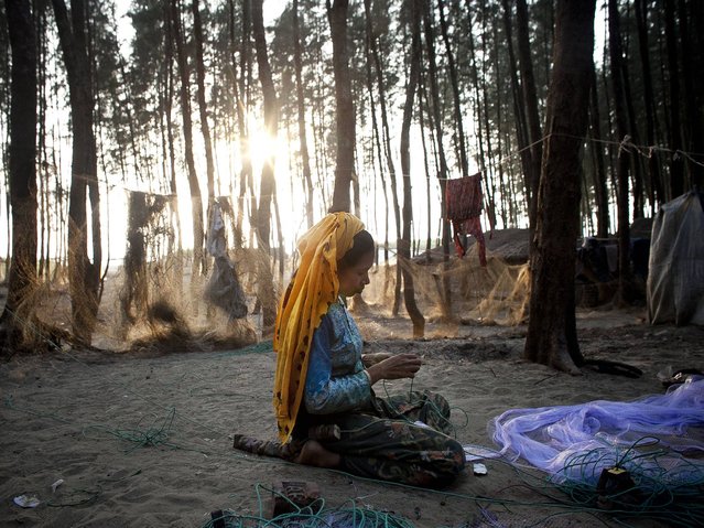 32 year old Mahada Khatum repairs a fishing net outside her home in the Shamalapur Rohingya refugee settlement in Chittagong district. Some years ago she escaped violence and discrimination from the Zomgara Baharchara village in the Meherulla district of Myanmar. (Photo by Getty Images/Stringer)