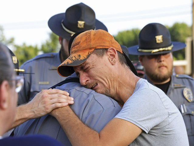 Bo Lanthrop, right, embraces a member of the Fordyce Police Department during a candlelight vigil in the parking lot of the Mad Butcher grocery store in honor of the victims of Friday's mass shooting, in Fordyce, Ark., Sunday, June 23, 2024. (Photo by Colin Murphey/Arkansas Democrat-Gazette via AP Photo)