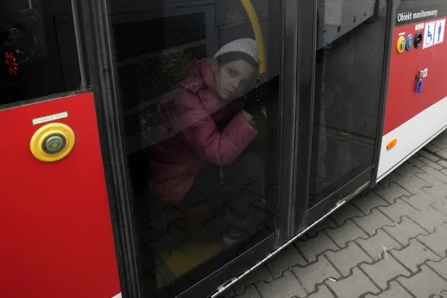 A young girl who fled the war in Ukraine sits on a bus to leave Korczowa border crossing, Poland, Sunday, March 6, 2022. (Photo by Czarek Sokolowski/AP Photo)