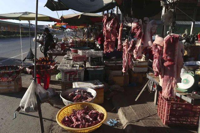 Cambodian vendors sell pork meats, vegetable and fish at a roadside market on the outskirts of Phnom Penh, Cambodia, Wednesday morning, December 8, 2021. (Photo by Heng Sinith/AP Photo)