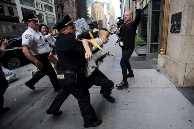 A protester is detained by New York Police Department officers during a rally for Eric Garner who was killed one year ago by police in New York July 17, 2015. Family and supporters on Friday marked the anniversary of the police killing of Garner with rallies and vigils demanding police reforms and justice in the controversial case. (Photo by Eduardo Munoz/Reuters)